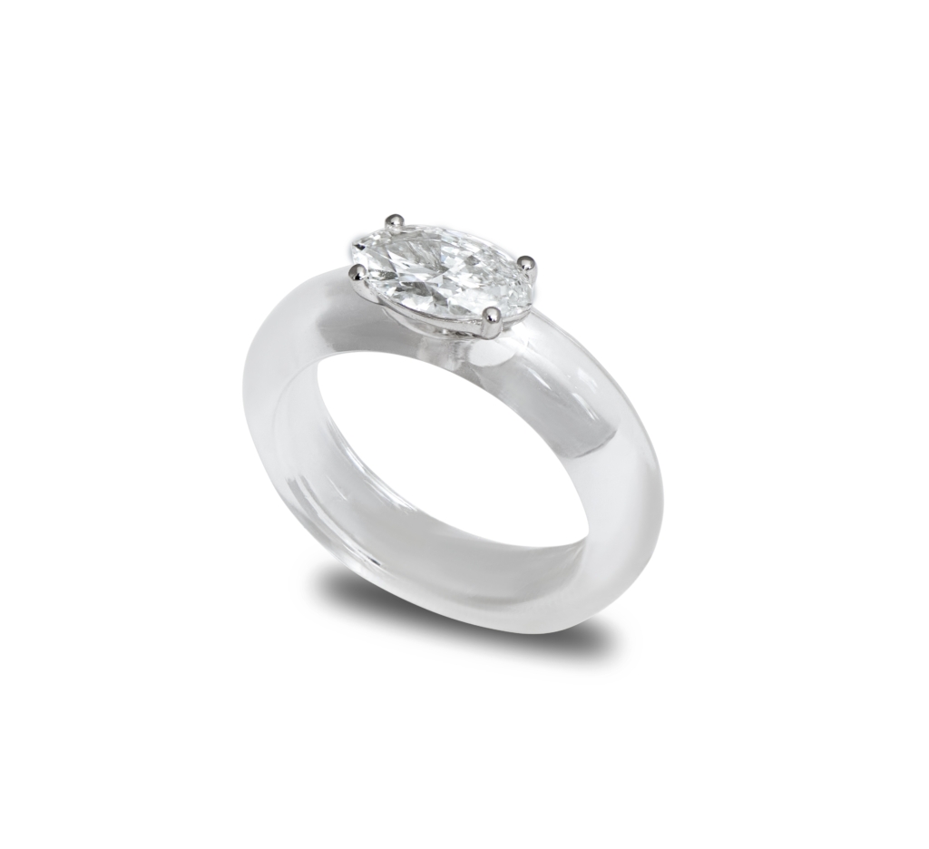 This image shows a sleek silver ring featuring a large oval-cut diamond set in a simple four-prong setting on a thick, polished band.